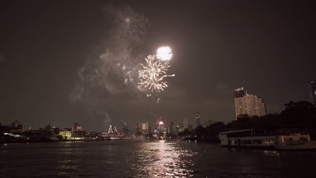 泰国曼谷，夜晚，在天空的映衬下，烟花在河边的建筑物上爆炸视频素材