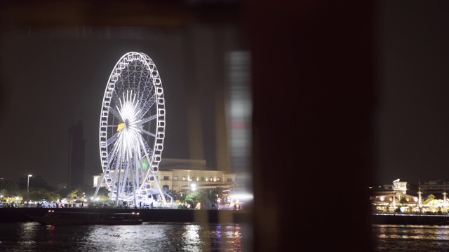 泰国曼谷，夜晚天空的映衬下，河边码头上灯火通明的摩天轮视频素材