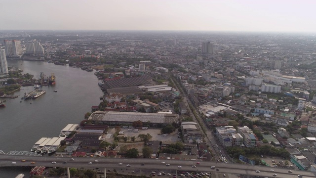 空中拍摄的车辆在城市河上的桥梁在晴朗的一天，无人机飞过城市景观对天空-曼谷，泰国视频素材