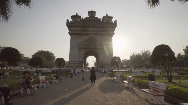 在老挝万象的阳光明媚的日子里，游客们在城市中著名的胜利门的小路上视频素材