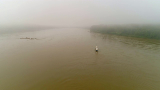 空中向前拍摄的船只在河中移动在大雾天气，无人机在水上对天空飞行-湄公河，老挝视频素材