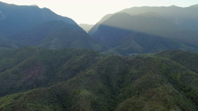 空中拍摄的田园诗般的绿色山脉对天空在日出，无人机向前飞行在郁郁葱葱的景观-琅勃拉邦，老挝视频素材