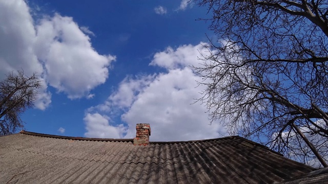 在一个晴朗的日子里，在一个多云的天空下，瓦片屋顶上的旧砖烟囱的时间流逝。视频素材