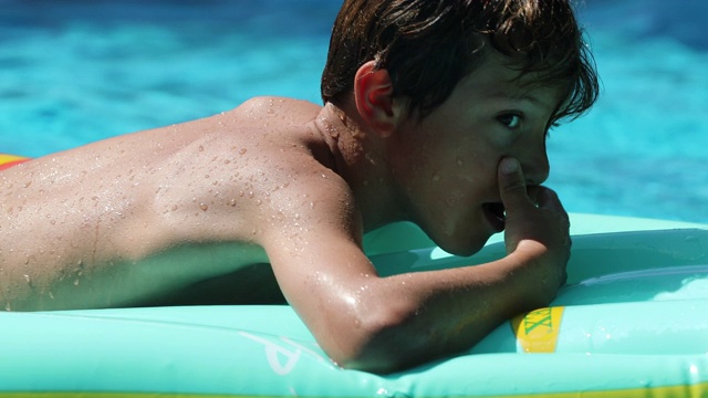 小男孩在充气床垫上玩的孩子在游泳池视频素材