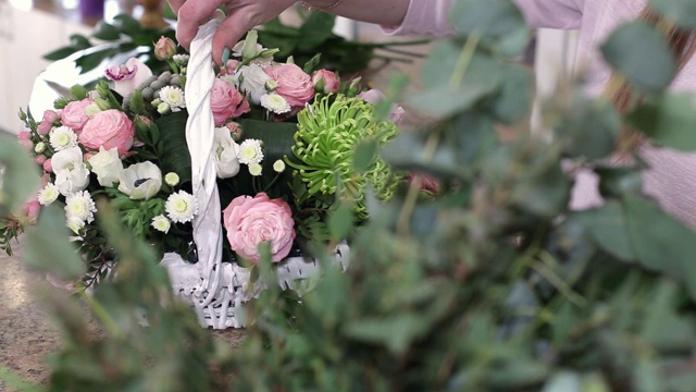 年轻女子花商制作美丽的花花束玫瑰在白色的篮子视频素材