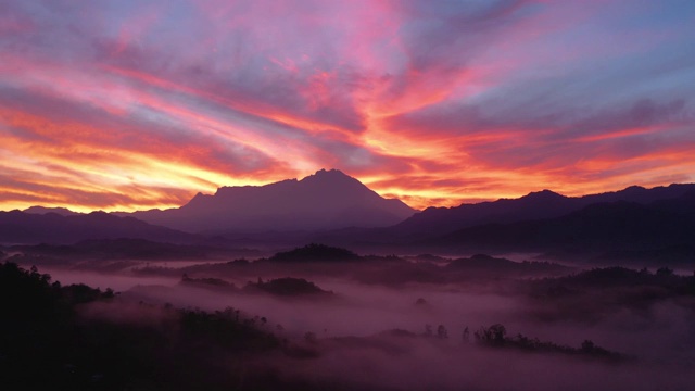 令人惊叹的美丽燃烧的天空日出与基纳巴卢山为背景在云雾缭绕的热带雨林在沙巴州，婆罗洲视频素材