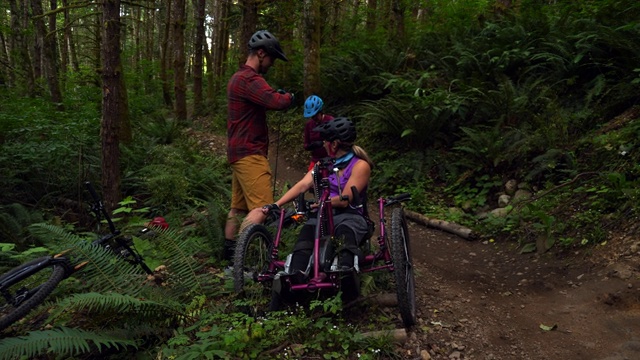 MS朋友帮助女人在适应性山地自行车固定链而骑视频素材