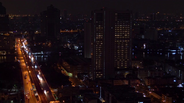 4K高角度鸟瞰图的未来摩天大楼和道路上的交通与照明的夜晚灯在市中心区。都市与商业金融大厦和城市街道的夜晚。视频素材