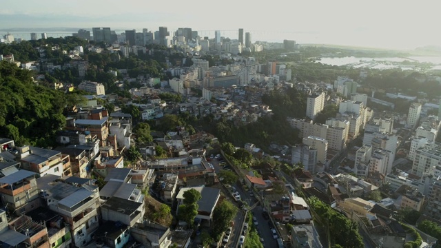 空中飞过山顶的贫民窟，飞向背景中的里约热内卢市中心的高楼大厦视频素材