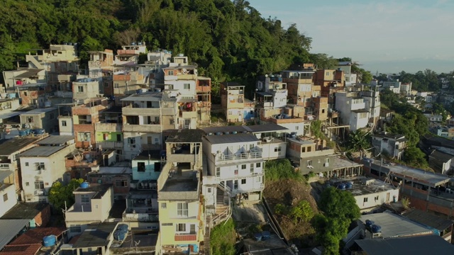 在巴西里约热内卢，日出时，空中追踪经过山顶上阳光明媚的贫民窟房屋视频素材