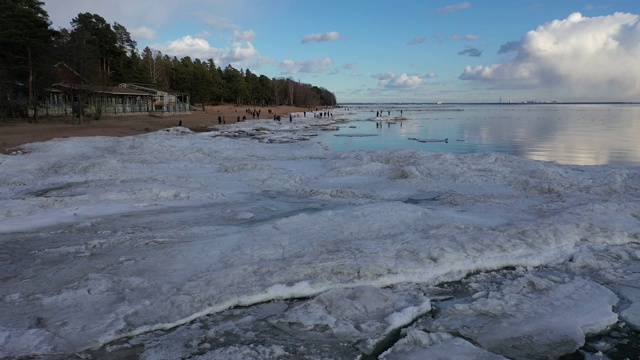 春天在海岸线上飞行，海浪上漂浮着冰块视频下载