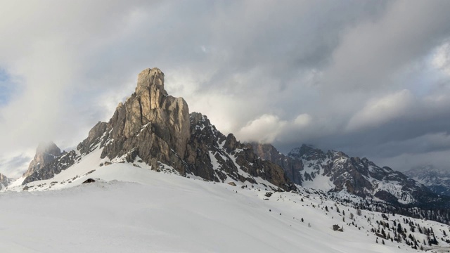 在冬天的一天，在被雪覆盖的山峰上移动的云的延时视频素材