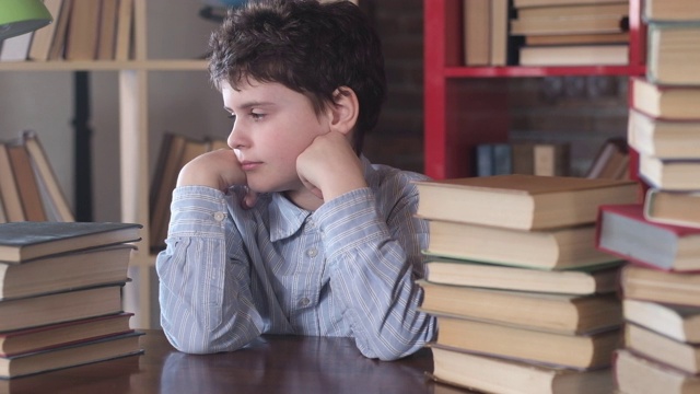 一个男生睡在桌子上。在学校的一堆书中叫醒一个孩子。视频素材