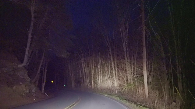 在乡村的高速公路上行驶，在夜间穿过山区的森林。视频素材