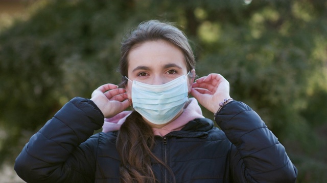 迷人的女孩戴上医用面具。深呼吸，看着绿色背景的摄像机。医疗保健理念视频素材