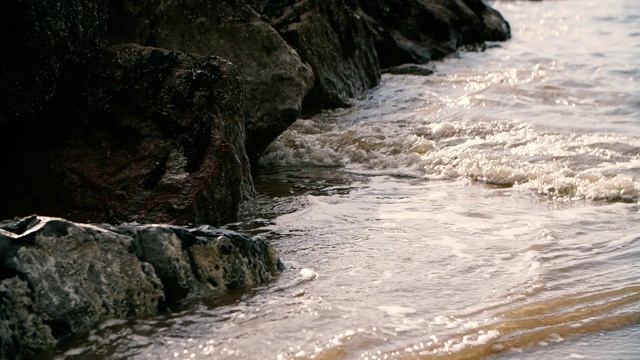 当潮水涌向海岸时，海浪撞击岩石的特写视频素材