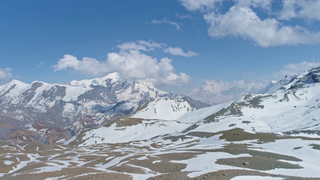 高原全景，蓝天中白色的山峰触云，地面上白雪皑皑的图案视频素材