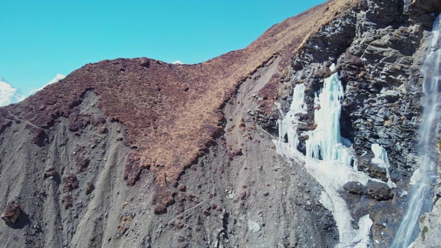 瀑布从冰崖落下，雪峰在地平线，河峡谷，全景视频素材