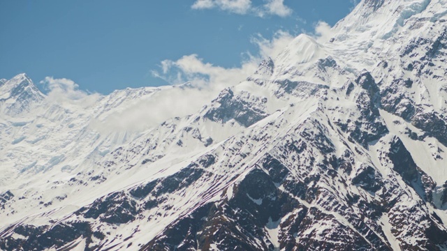 雪山山顶的蓝天上，两只鸟的剪影在高高的云中飞翔视频素材