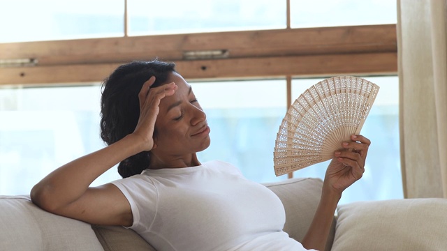 疲惫的千禧混血女孩挥舞着扇子，感觉很热。视频素材