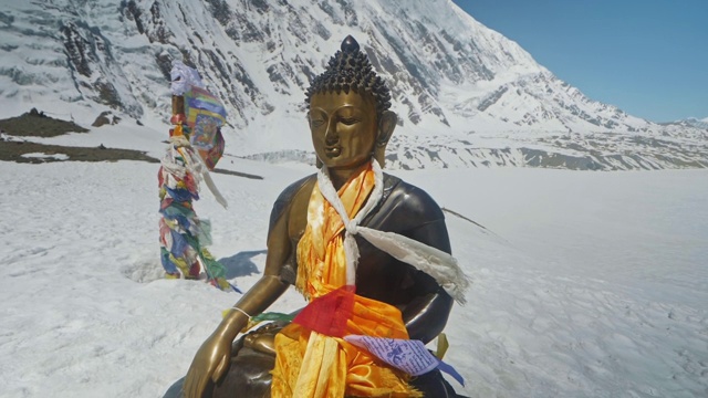 在蓝天白云的映衬下，青铜佛像在雪山上闪闪发光视频素材