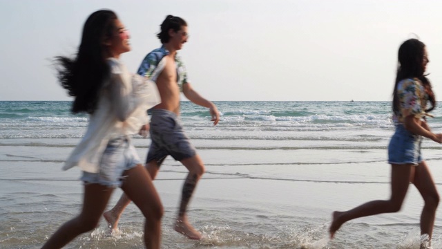 亚洲十几岁的男孩和女孩快乐地在海边海滩夏天跑步。年轻的亚洲玩跑步乐趣和周年庆典。4K分辨率和慢镜头。视频素材