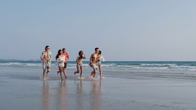 亚洲十几岁的男孩和女孩快乐地在海边海滩夏天跑步。年轻的亚洲玩跑步乐趣和周年庆典。4K分辨率和慢镜头。视频素材