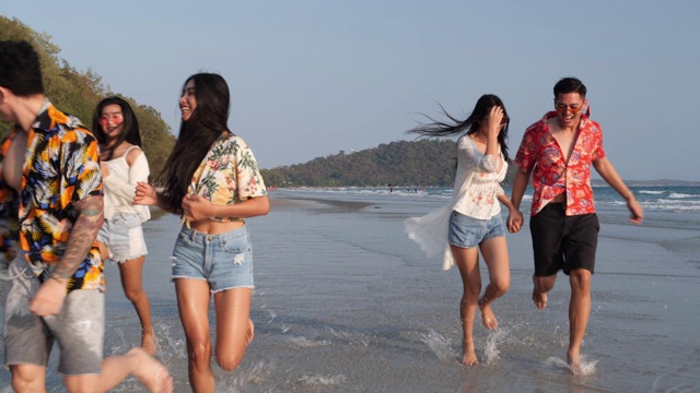 亚洲十几岁的男孩和女孩快乐地在海边海滩夏天跑步。年轻的亚洲玩跑步乐趣和周年庆典。4K分辨率和慢镜头。视频素材