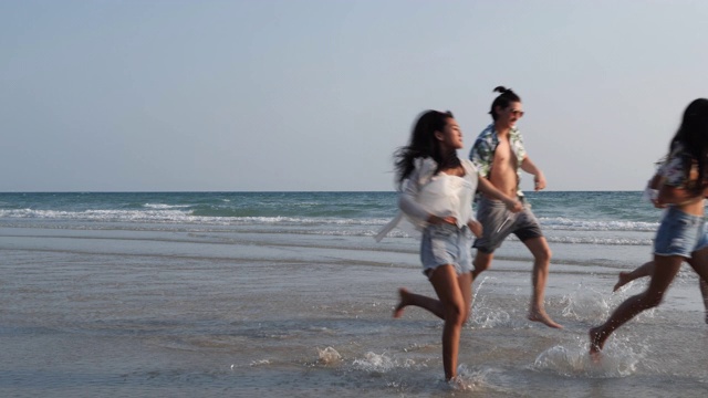 亚洲十几岁的男孩和女孩快乐地在海边海滩夏天跑步。年轻的亚洲玩跑步乐趣和周年庆典。4K分辨率和慢镜头。视频素材