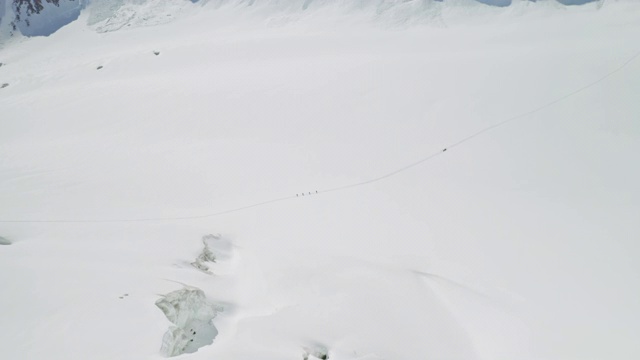 可怕的鸟瞰图，登山运动员在雪白色的山坡上徒步旅行视频素材