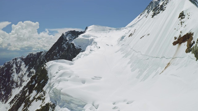 高地鸟瞰全景，登山家的小径通向白雪皑皑的山坡视频素材