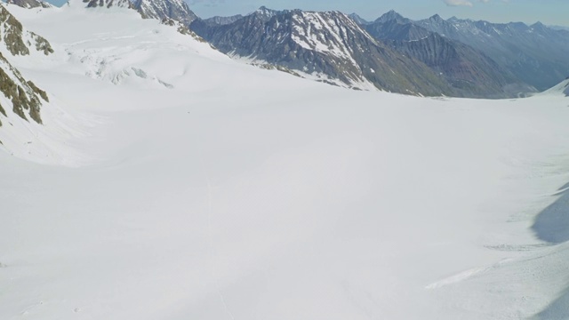 高山探险队翻越宽阔的雪坡，阳光明媚的高原风景优美视频素材