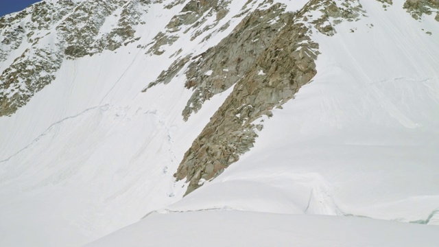 令人敬畏的岩石雪山高耸在蓝天，白色的冰川在阳光下闪闪发光视频素材