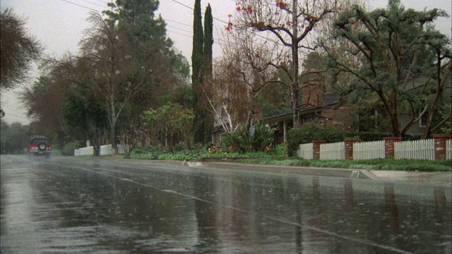 多云的一天。下雨，下雨，潮湿，下雨的街道与交通。社区住宅区绿树成荫的街道与红色野马奔跑的r-l。注意:德州盘子视频素材