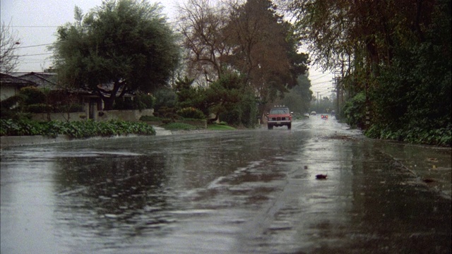 多云的一天。下雨，下雨，潮湿，下雨的街道与交通。社区住宅区绿树成荫的街道与红色野马奔跑的r-l。注意:德州盘子视频素材