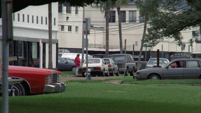 红色野马对着镜头，不稳定地开着l-r，穿过城市街道，两个男人在卡车里视频素材