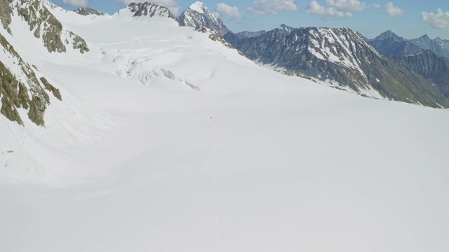 高山全景，探险队涉水走过永远积满积雪的宽阔山坡视频素材