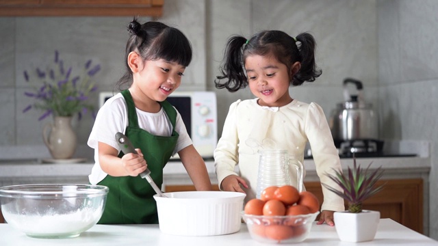 孩子们喜欢在厨房做饭。快乐的亚洲孩子们正在厨房里准备生面团、面包和烤饼干。视频下载