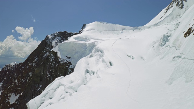 鸟瞰全景，登山运动员的小径通向白雪覆盖的巨大山坡视频素材