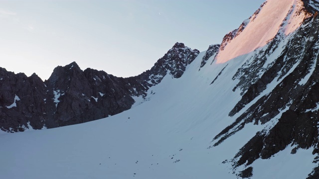 美丽的高山全景，陡峭的冰冻雪坡，晨光中的岩石山脊视频素材