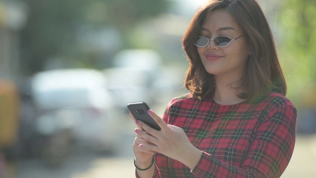 面对快乐年轻美丽的亚洲女商人在户外使用电话视频素材