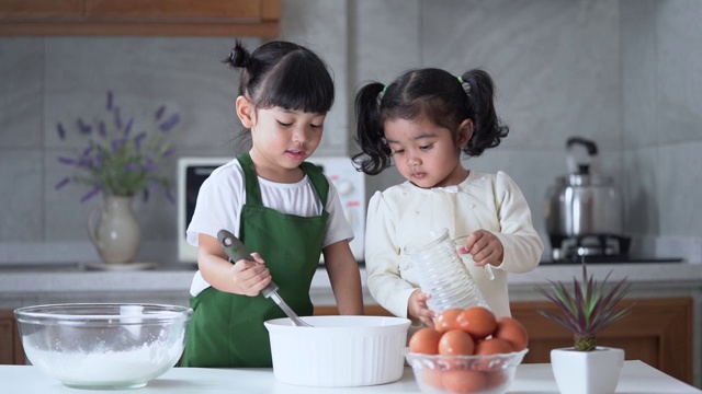 孩子们喜欢在厨房做饭。快乐的亚洲孩子们正在厨房里准备生面团、面包和烤饼干。视频素材