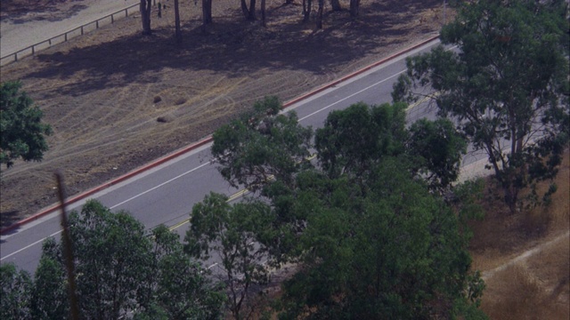 从山的角度到街道的单车道高速公路两旁是树和草地/警车没有灯的驾驶在r-l滑转弯停止[射击1311-07至16匹配]视频素材