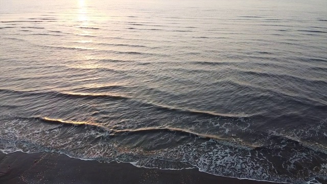 日落时海浪冲到海滩上视频素材