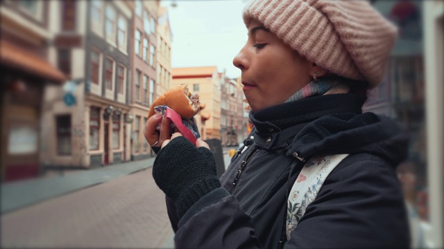 年轻饥饿的女人在街上吃快餐，特写视频素材