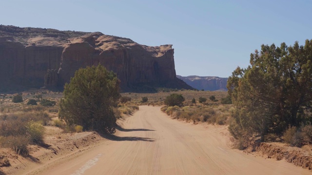 在纪念碑谷的红岩间的沙漠中尘土飞扬的道路上行驶视频素材