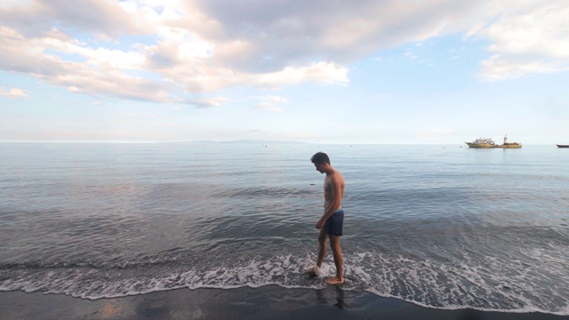 夏日的海滩上站着走着的男子。视频素材