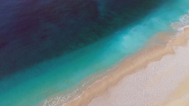 空中鸟瞰完美的绿松石海滩。Сlear蓝色的海水-完美的暑假。飞过白沙空旷的海滩视频素材