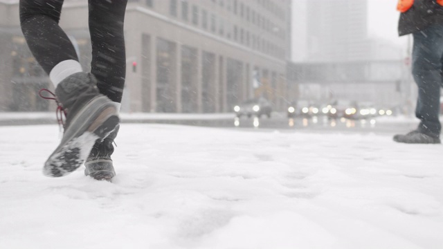 低角度拍摄的女人在城市的雪中行走视频素材