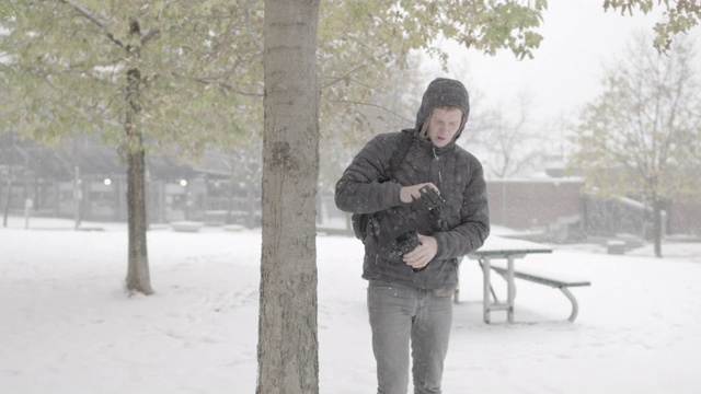 一个年轻人在雪地里调整相机设备的慢动作镜头视频素材